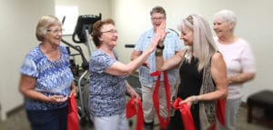 A group of senior women holding resistance bands interact with a female fitness instructor