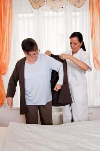 nurse helping senior put on jacket