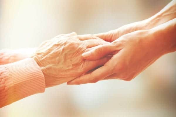 A close-up photo of two pairs of hands outstretched in an embrace