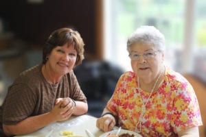 Mother and daughter together in dining room of senior community center.
