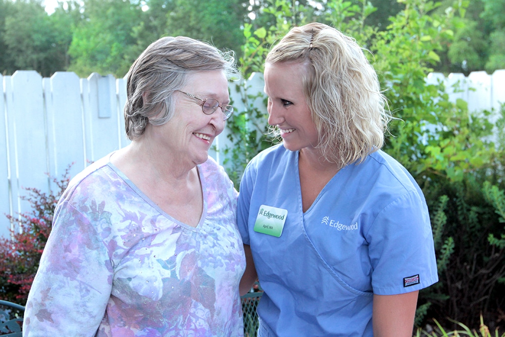 A resident and an Edgewood caretaker stand together outside.