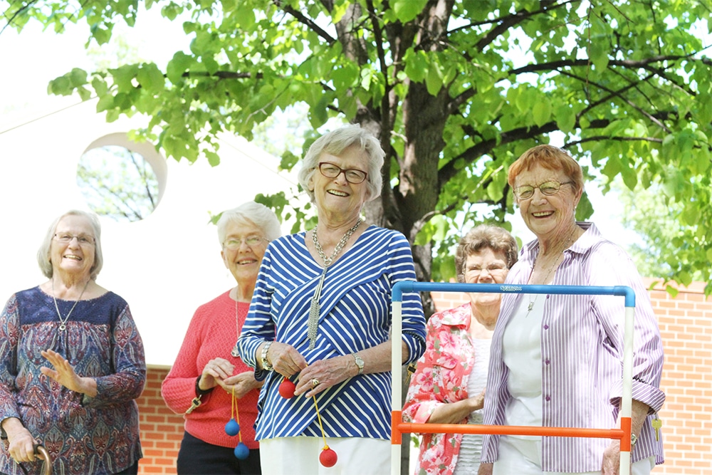 Five senior women play game outside.