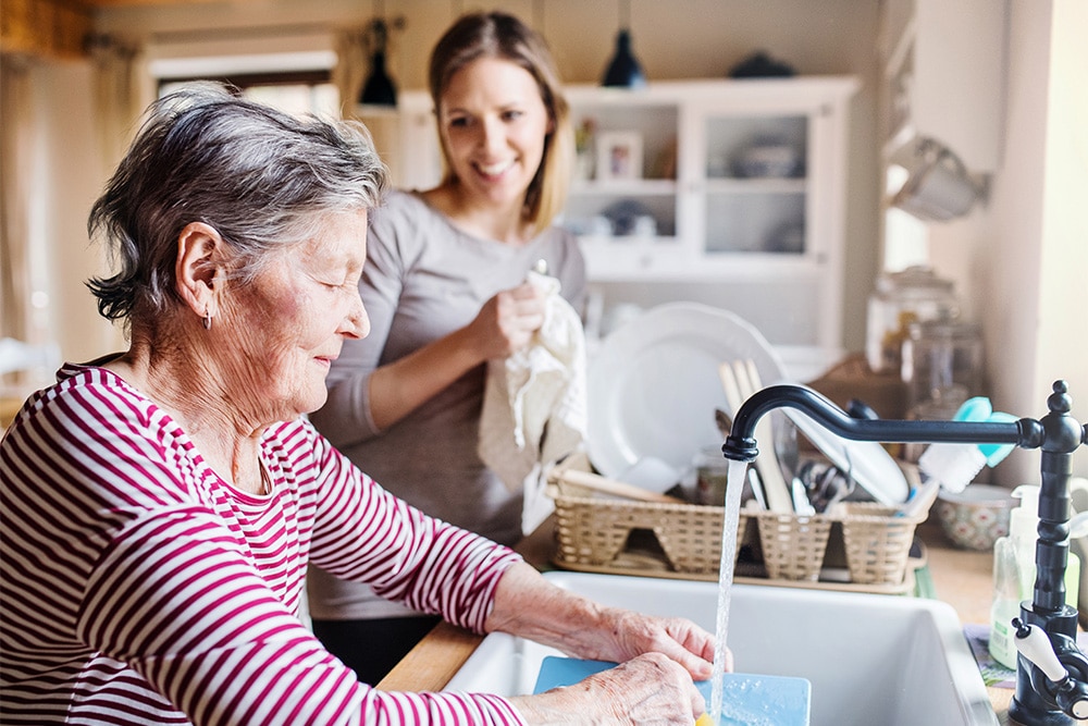 An elderly woman and younger woman washing dishes.