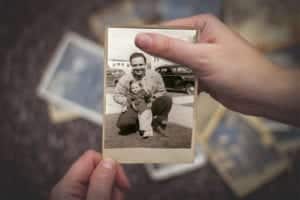 Hands holding a black and white photo of a father and daughter from the 1950s