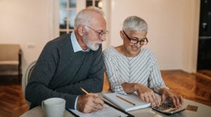 A senior man and senior woman doing financial planning with notepads and a calculator on a