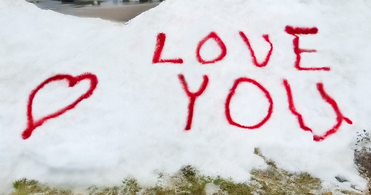 A message saying “love you” written in red paint in a snow bank