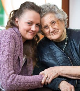 A young woman and senior woman lean in to pose for a photo