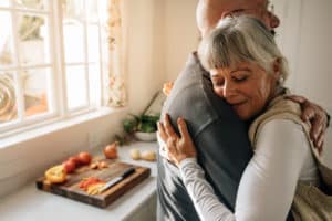 A senior man and woman embrace one another in a modern kitchen