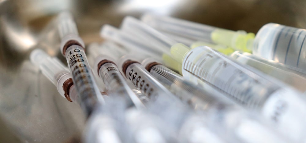 A group of vaccine syringes on a metal tray.