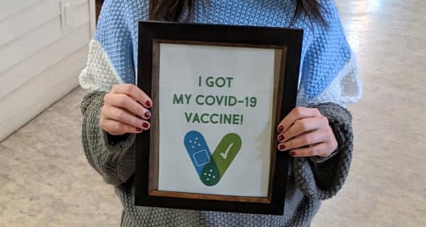 A closeup of a young female Edgewood Healthcare employee’s hands holding a sign that says, “I got my COVID-19 vaccine!”