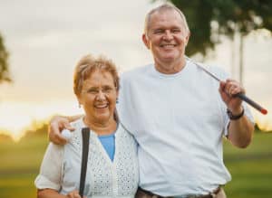 A senior man and woman embracing each other while golfing