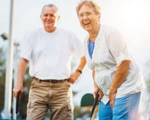 Older couple smile while golfing.