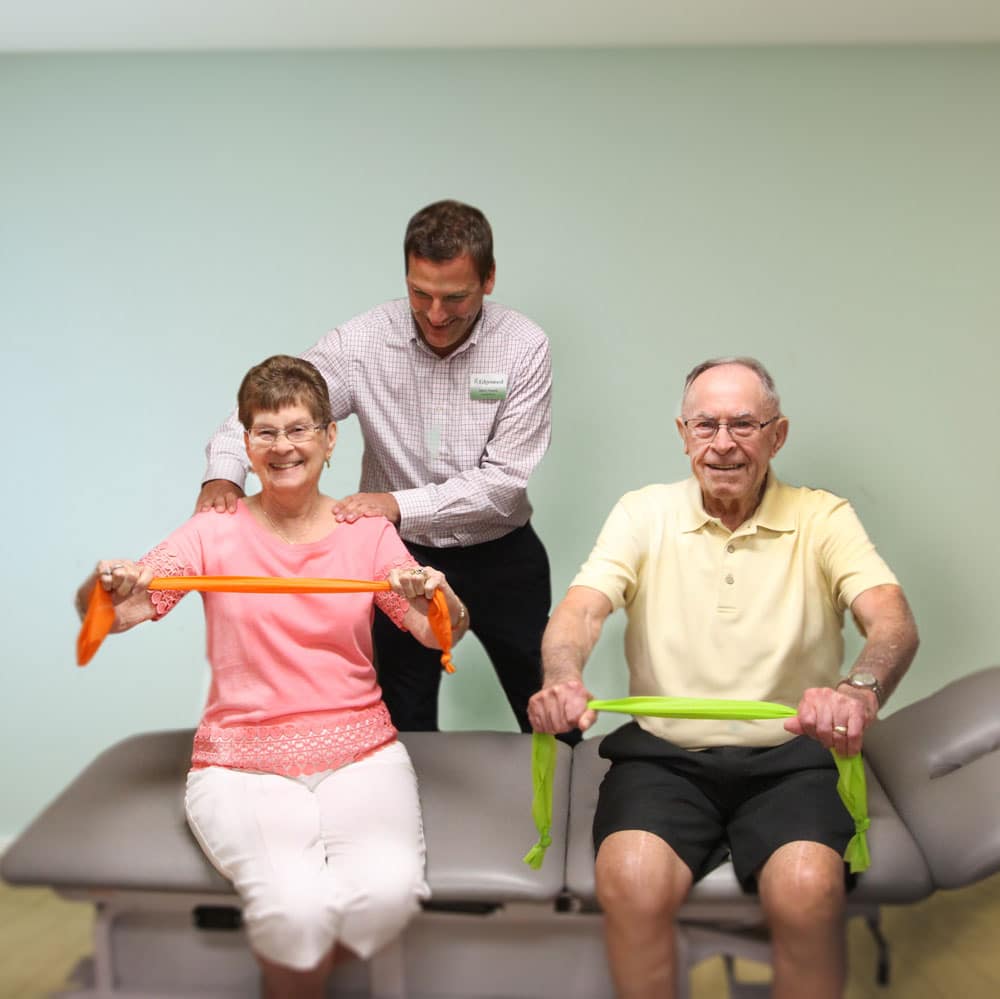Older couple doing physical movement with therapy bands.