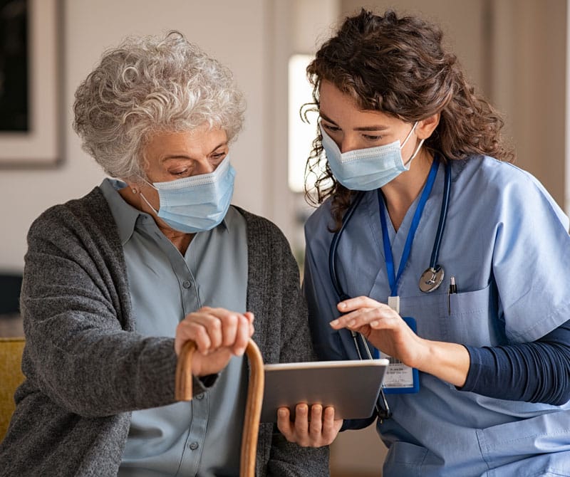 Female doctor and senior woman going through medical record on a digital tablet during a home health visit