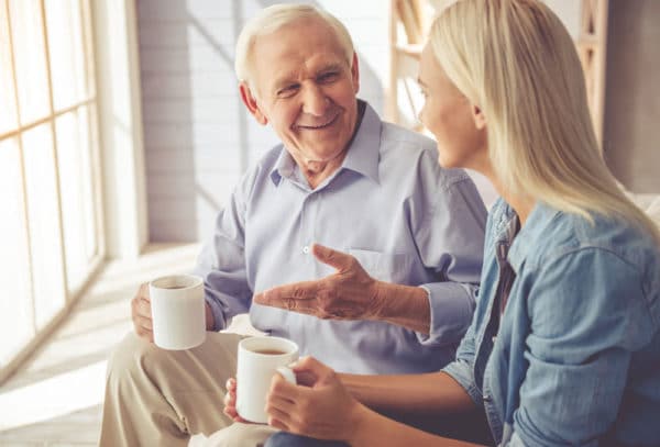 Senior father talks to his young daughter and smile in conversation.