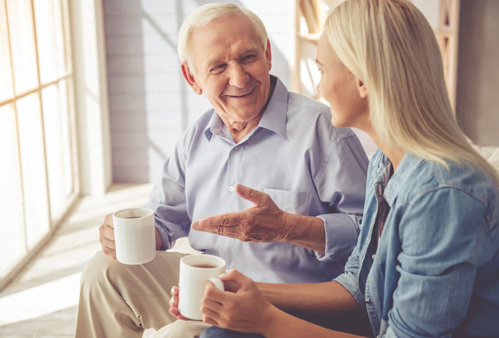 Senior father talks to his young daughter and smile in conversation.