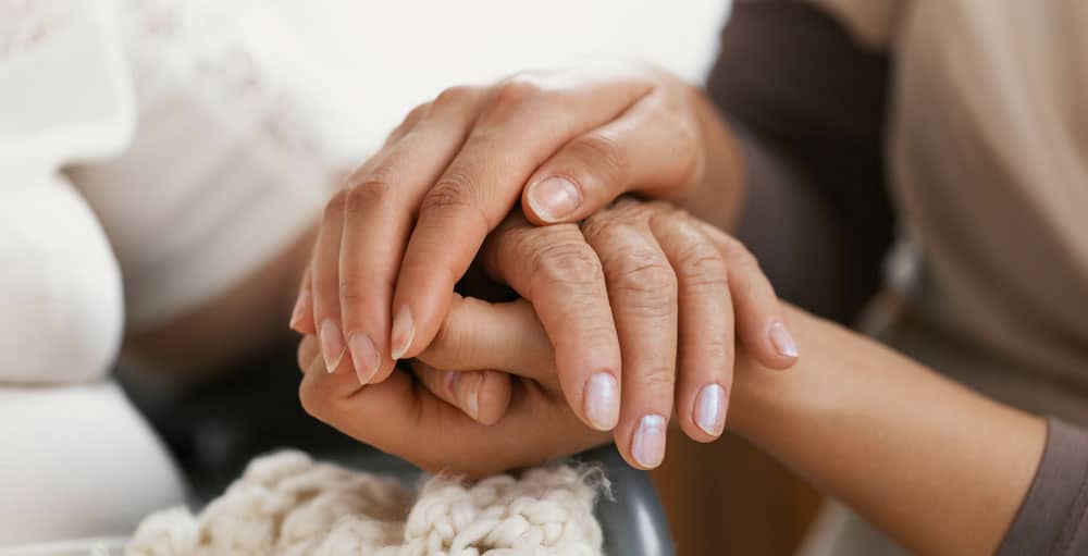 Nurse-holding-seniors-hand A closeup of a nurse holding a senior woman’s hand