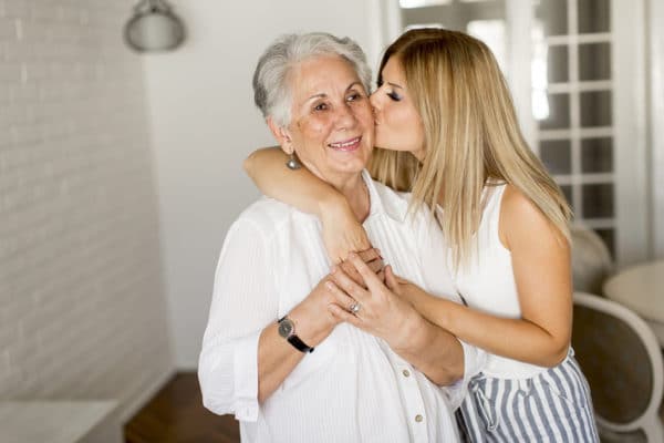 Female senior receiving kiss on cheek by female loved one