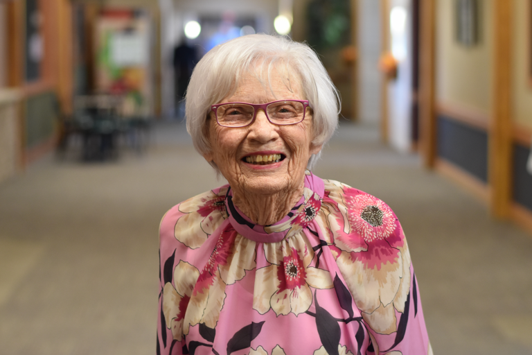 a happy senior female wearing a pink flowered shirt