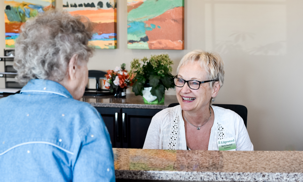 receptionist talking with senior at desk