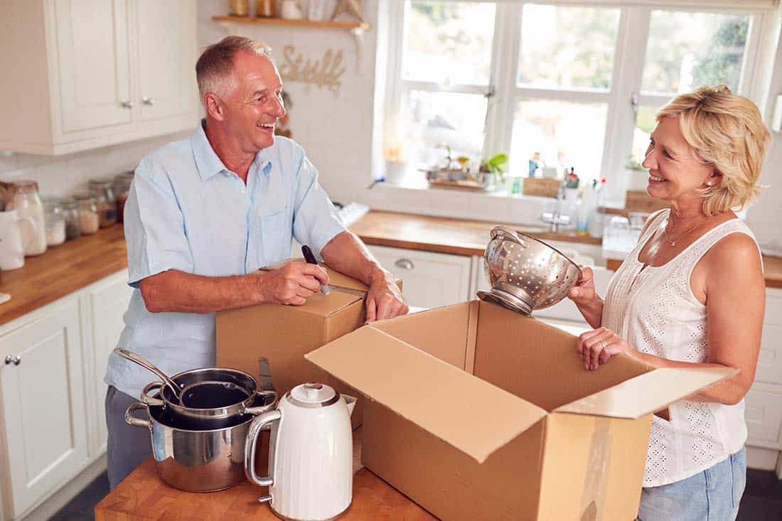 Senior couple putting kitchen items into boxes