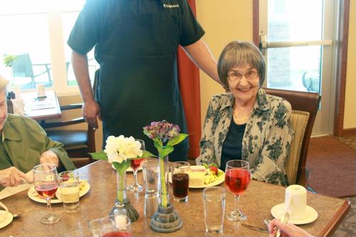 Senior females seated at dining table next to staff