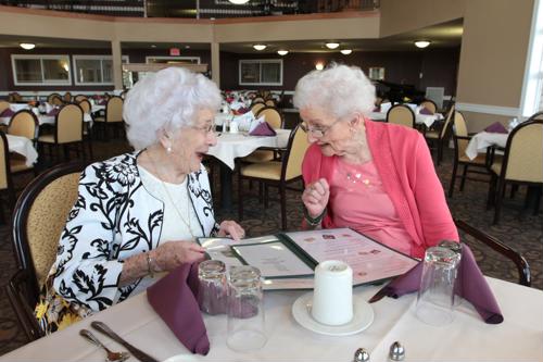 Two female seniors seated at dining table with menu