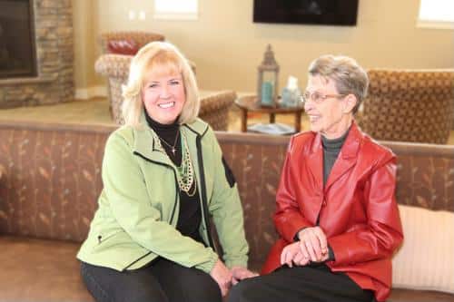 Female wearing green jacket next to senior wearing red leather jacket
