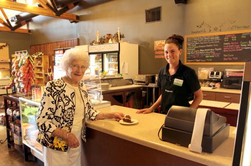 Female senior purchasing pastry item with female staff