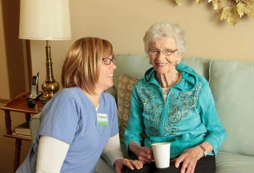 Smiling senior next to staff wearing blue scrubs