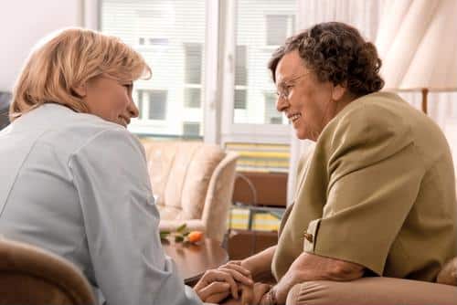 Female clinician holding hands of female senior
