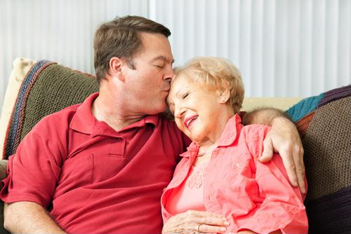 Male kissing forehead of senior female