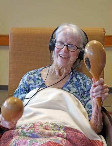 Senior female wearing headphones holding maraca