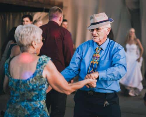 Senior male wearing hat dancing with senior female at wedding