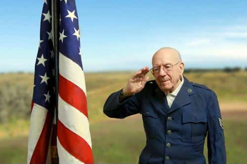 Senior male wearing army uniform saluting American Flag