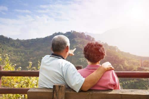 Male and female seated on bench looking at hillside