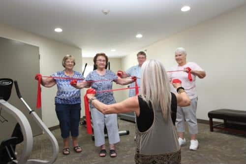 Seniors holding red bands with exercise instructor