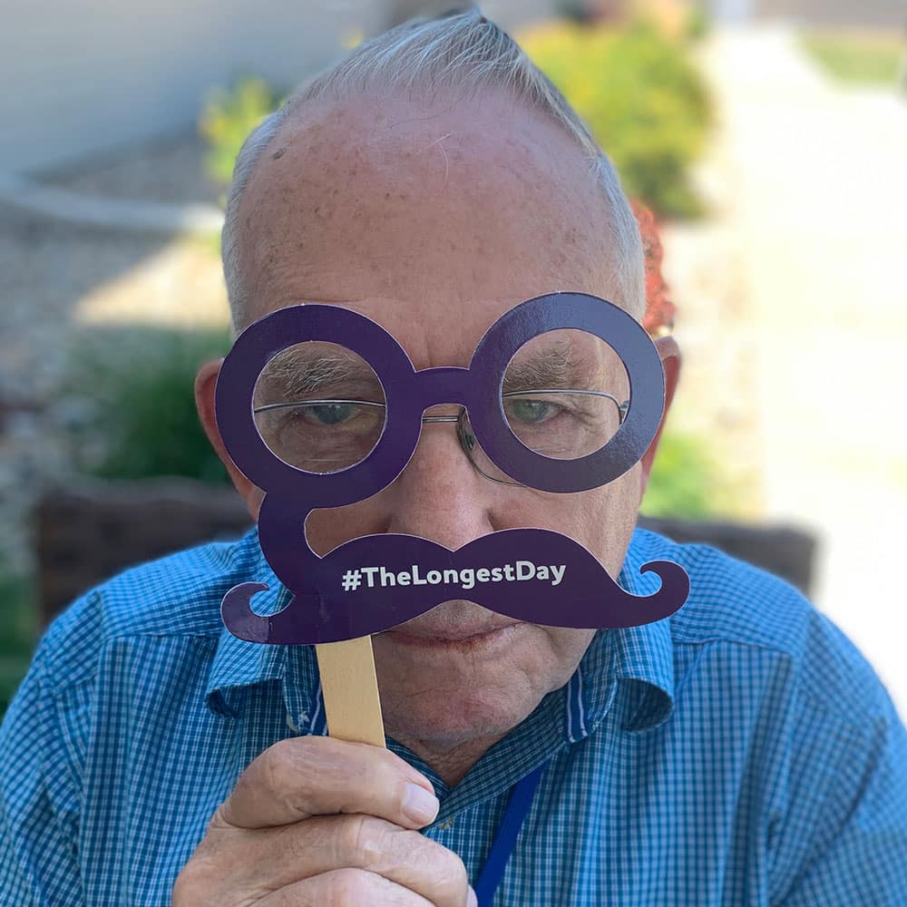 Senior male holding paper glasses connected to paper mustache