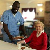 Senior female next to caregiver offering cookies