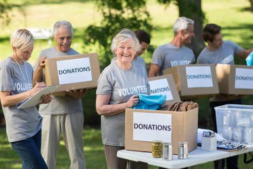 Seniors wearing volunteer shirts holding donations boxes