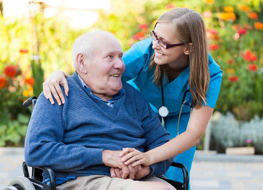 Senior male in wheelchair next two female clinical staff
