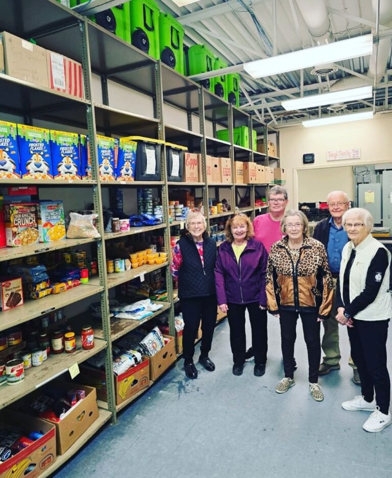 Senior living residents standing near a supply of food