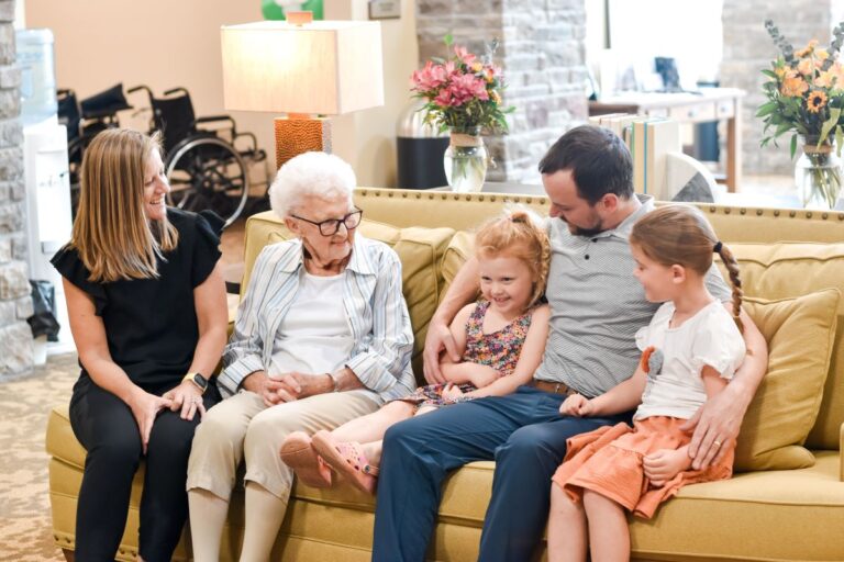 Family seated with senior resident on couch