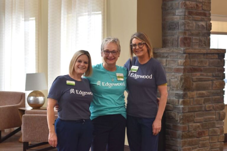 Three female Edgewood staff wearing Edgewood Branded t-shirts