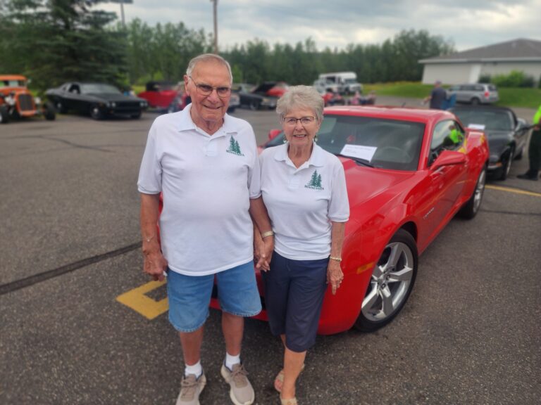 resident couple pictured in front of a sports car