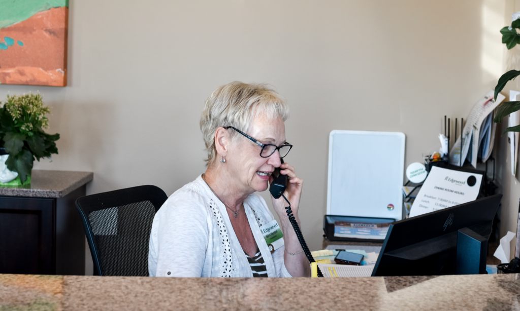 female receptionist sitting at a computer talking on the phone