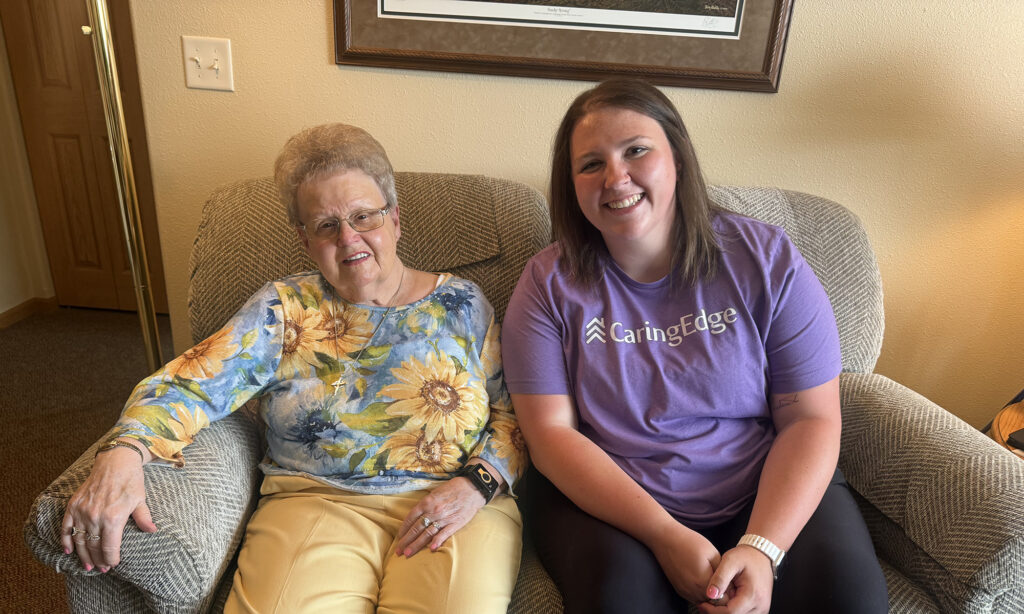 Older woman and her CaringEdge staff smiling together while seated side by side.